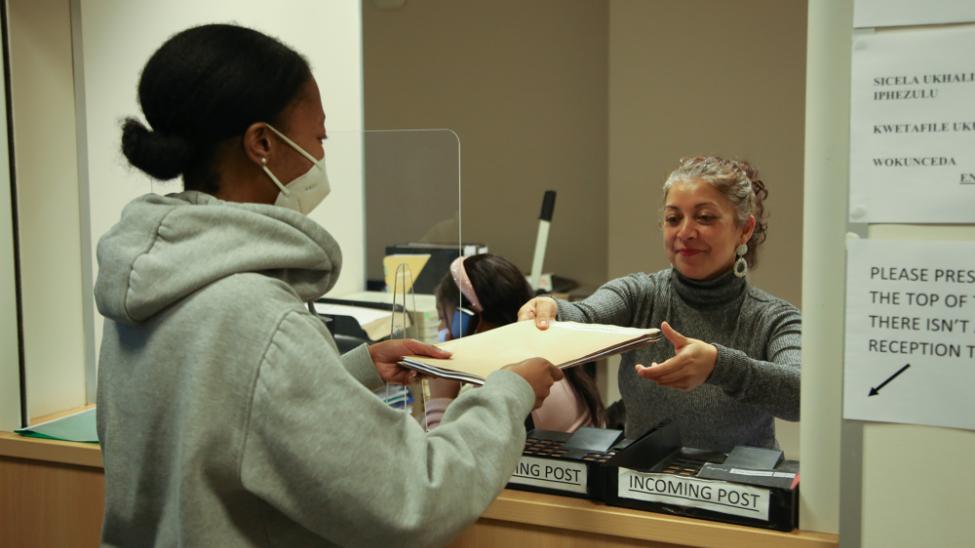 Two women sharing legal files over a counter