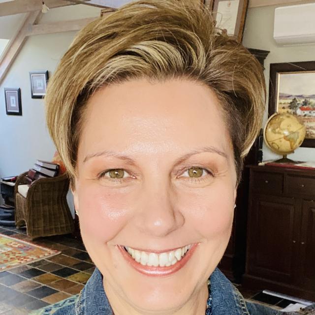 Woman in denim jacket faces camera smiling