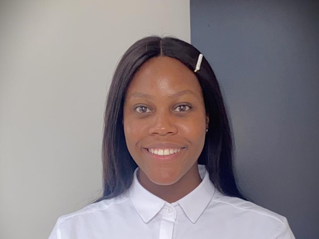 Thato Muzola stands against a grey and white background