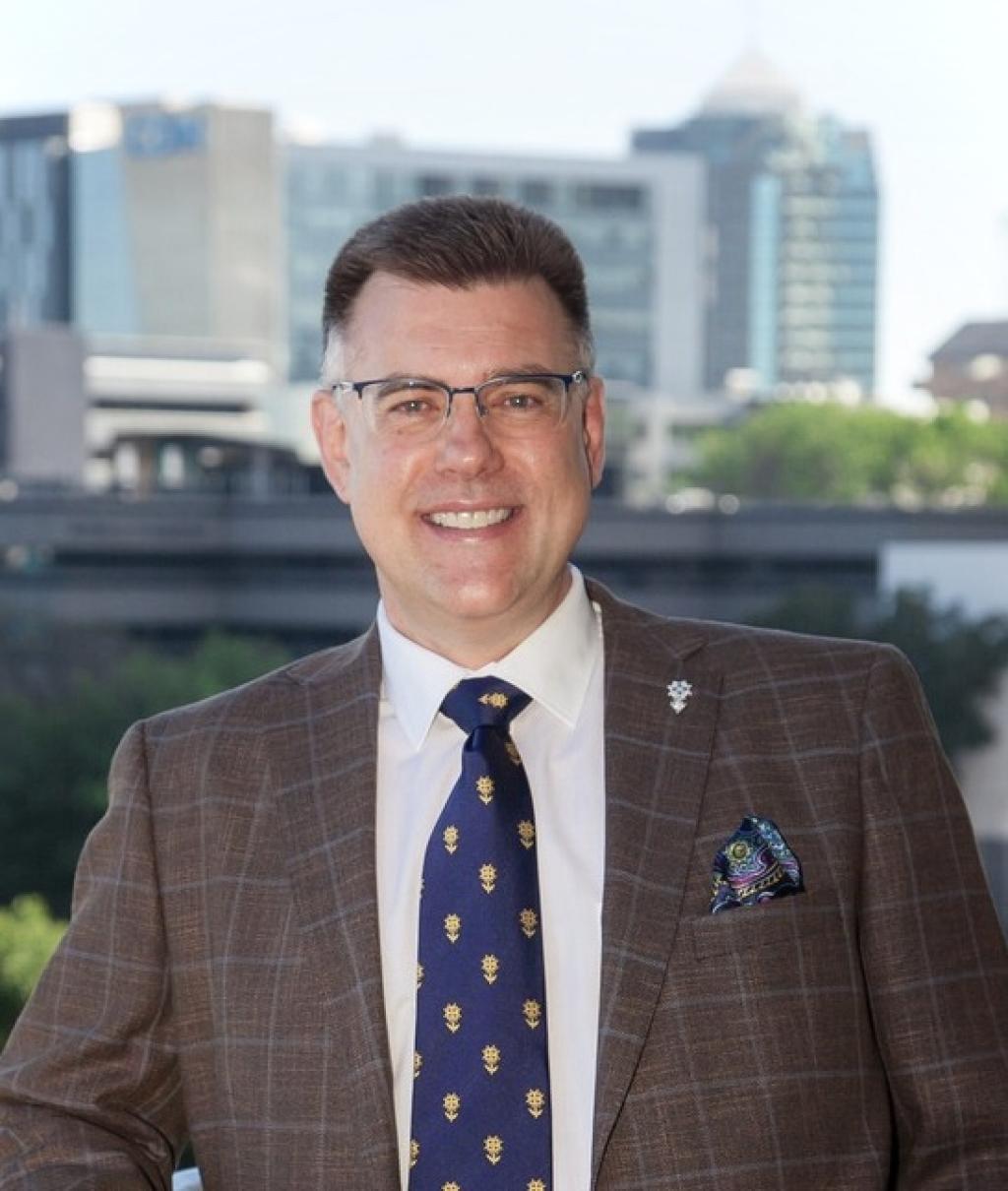 Professor Francois du Toit, facing camera wearing glasses, brown jacket and blue and gold tie